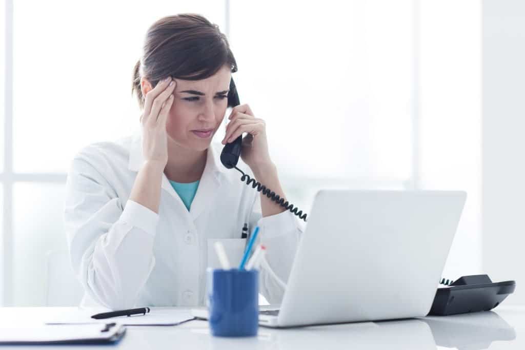 woman-holding-temple-while-on-the-hone-and-looking-at-laptop