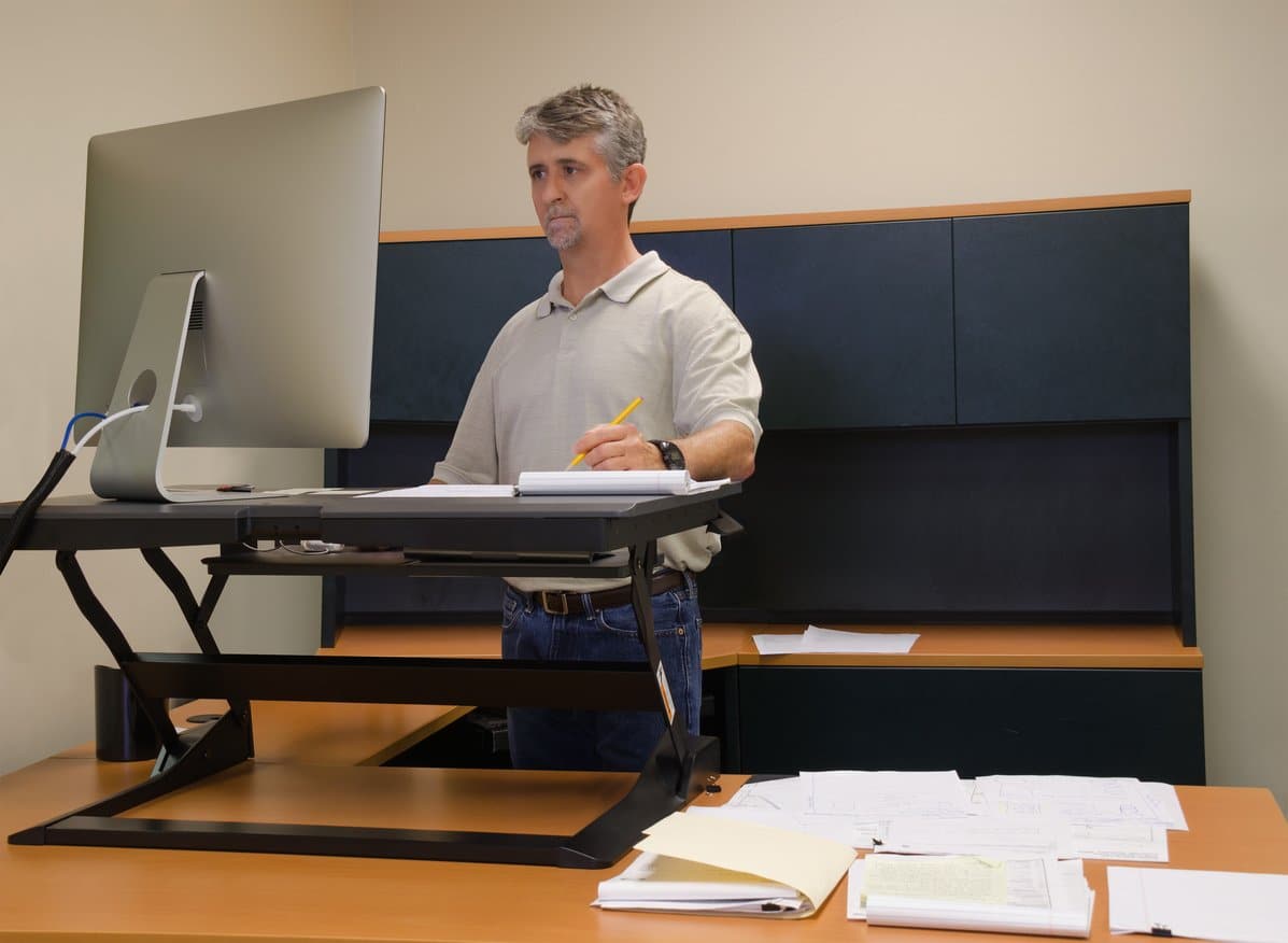 man-using-standing-desk-with-computer-monitor-at-work-office-with-no-windows