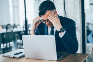 male businessman having headache due to long exposure to fluorescent lights