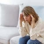 woman-holding-temples-while-sitting-on-couch-at-home