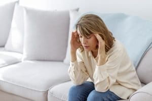 woman-holding-temples-while-sitting-on-couch-at-home