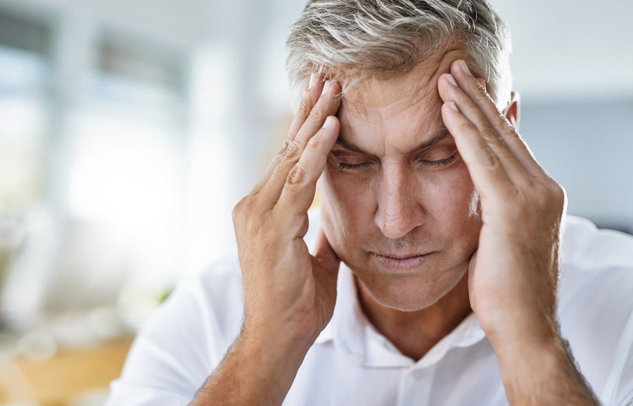 man-holding-sides-of-head-with-eyes-closed-suffering-from-headache