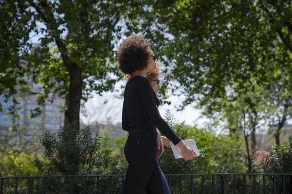 two-women-walking-outdoors-through-sunny-path-with-trees